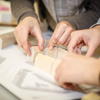 Studierende platzieren Holzbausteine ihres Holzmodells.
