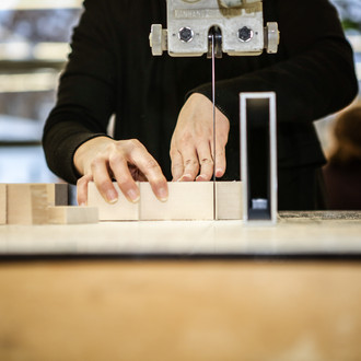 Eine Person benutzt eine Holzsäge und schneidet ein Holzbaustein durch.